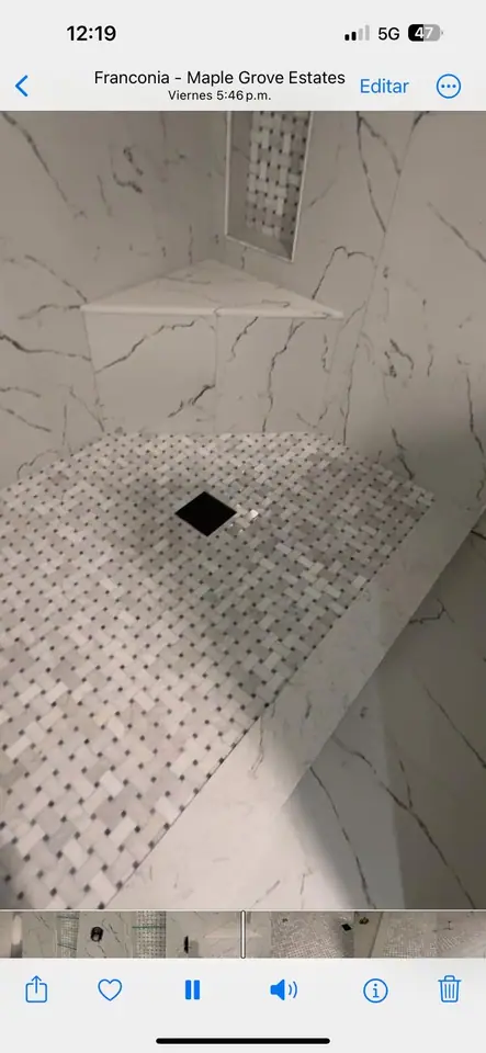 Walk-in shower with marble walls, mosaic floor, and a tiled corner bench